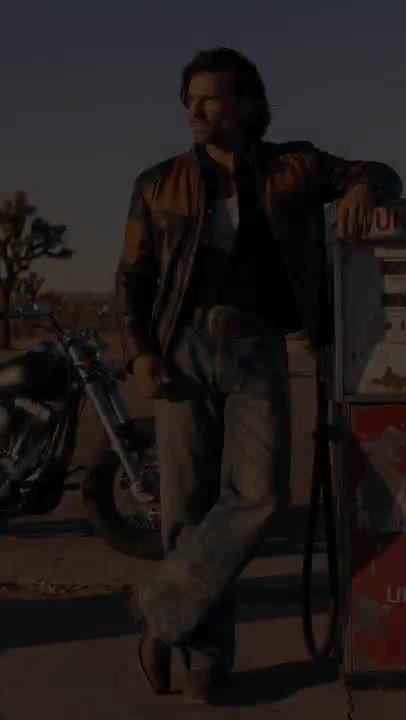 Man in a leather jacket beside a motorcycle